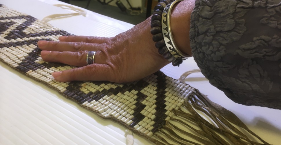 A hand laid across a beaded Wampum belt 